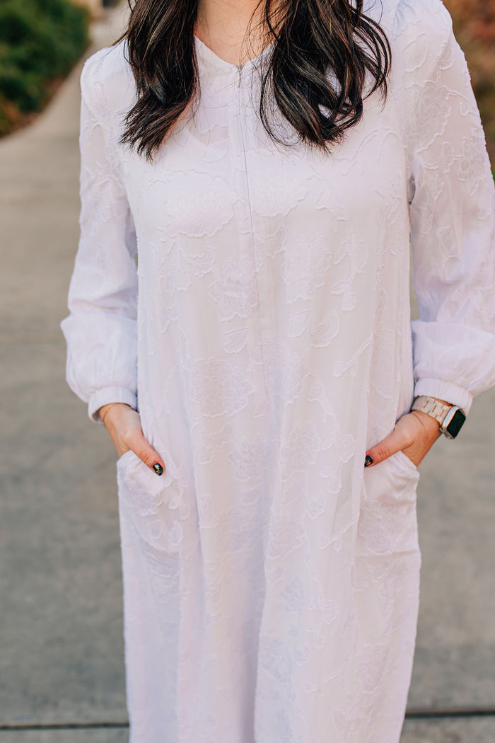 Long white dress with floral appliques and zipper front.