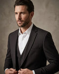 Man wearing a dark suit and white shirt against a neutral background