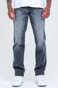 A person wearing B Couture Beckenham Straight Fit Stretch Denim Jeans in grey and white sneakers stands with arms at their sides against a plain light background, showing only the lower half of their body.