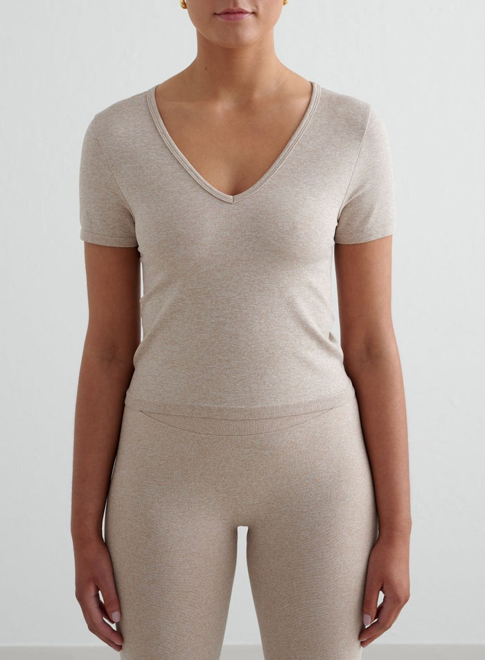 Beige melange Shape Seamless Short Sleeve -toppi imartelevalla V-pääntiellä ja tiukalla second skin -tuntumalla. [S - 175 cm]