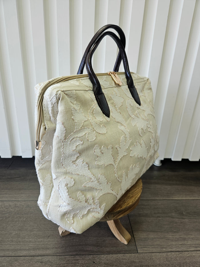 Beige zipper top purse with light beige appliques.