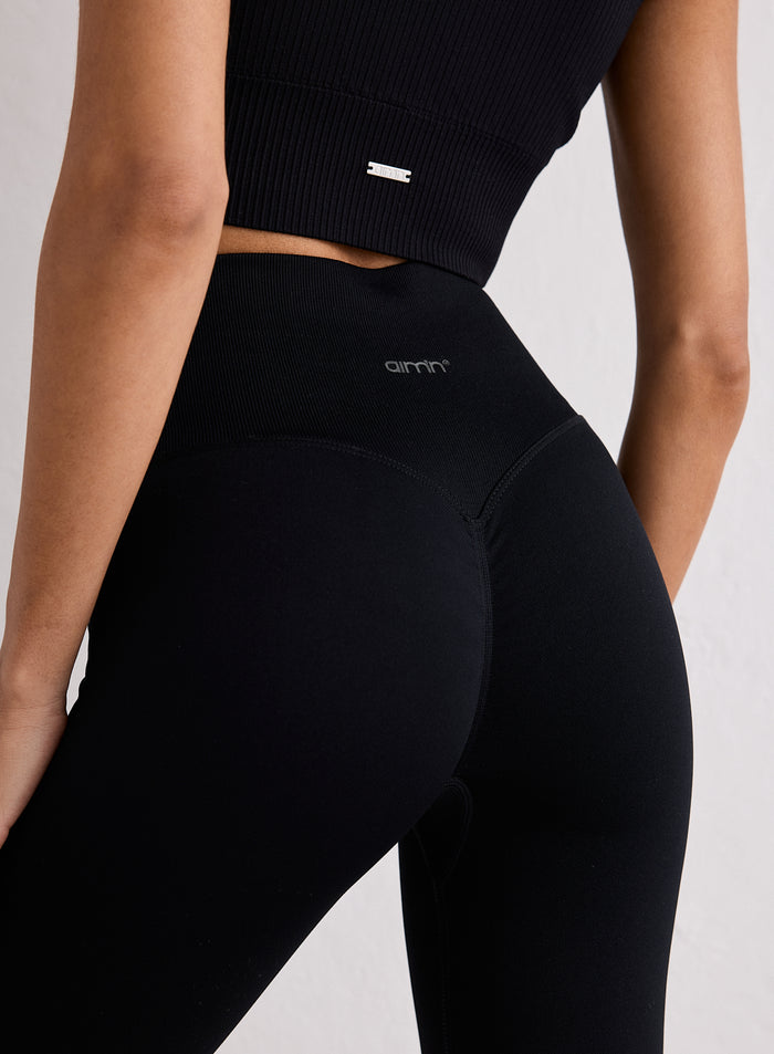 Lähikuva mustien Shape Seamless 7/8 Tights -treenitrikoiden takaosasta, joissa on invisible scrunch ja aim'n-logo [XS-170cm]