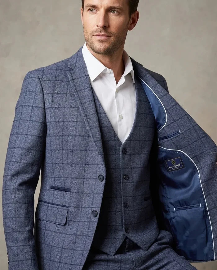Man wearing a blue checkered suit with a white shirt against a neutral background