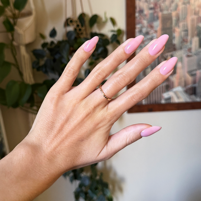 Flora Aura - Builder Gel on natural nails with glossy sheer cool-toned pink manicure in indoor setting with plants background
