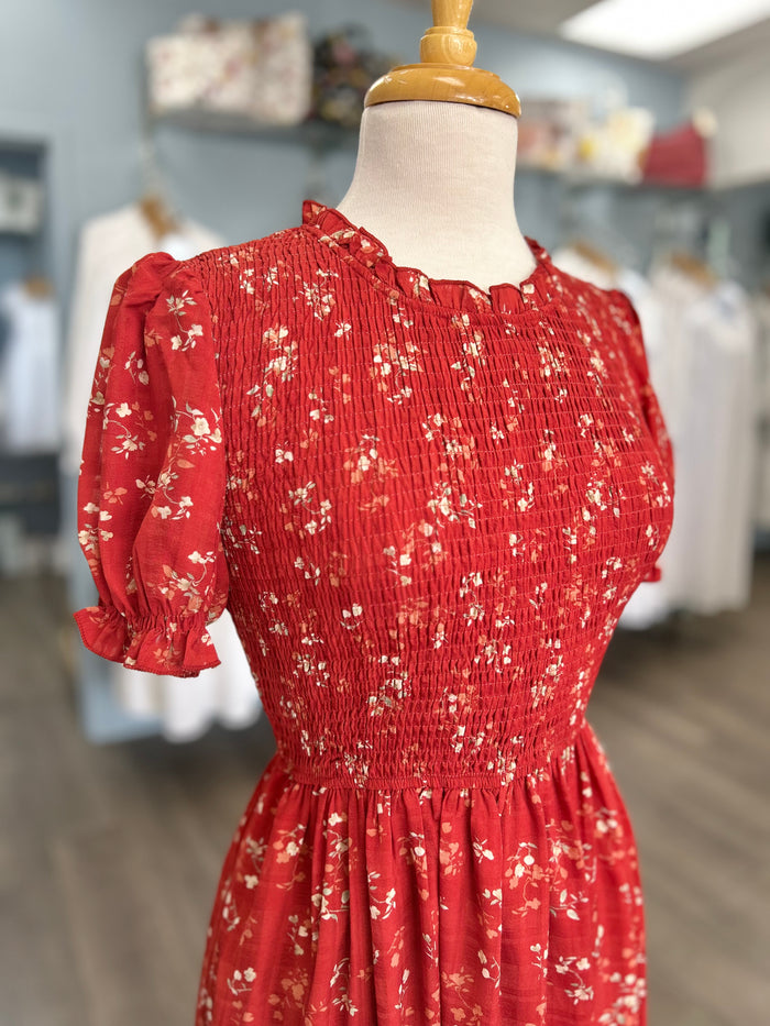 Red midi dress with floral pattern and smocked bodice.