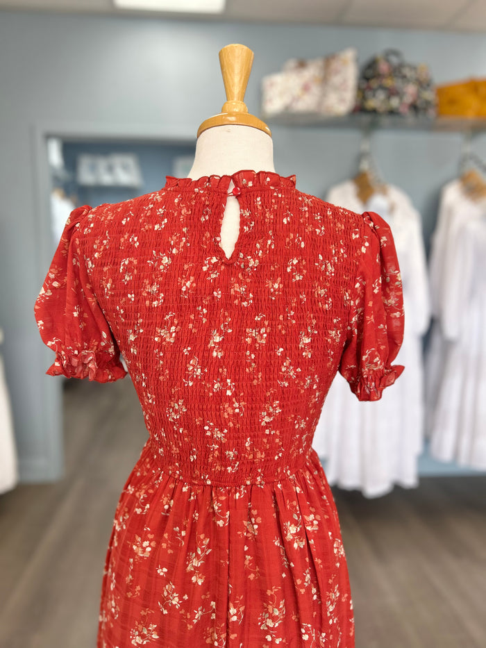 Red midi dress with floral pattern and smocked bodice.