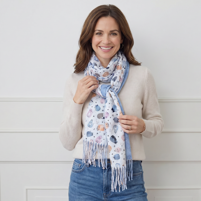 Woman wearing a patterned scarf and smiling against a white background