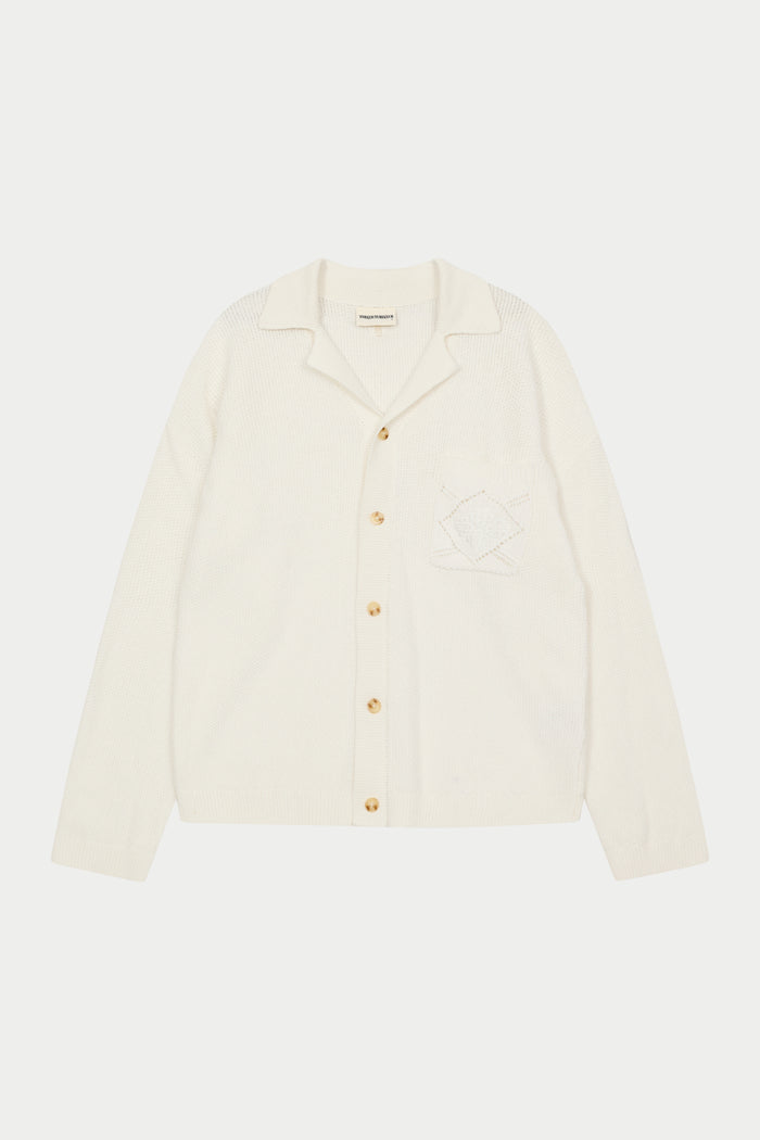 A long-sleeved off white shirt with a ribbed revere collar, crochet knit fabric, and a front left chest patch pocket with an embroidered emblem.
