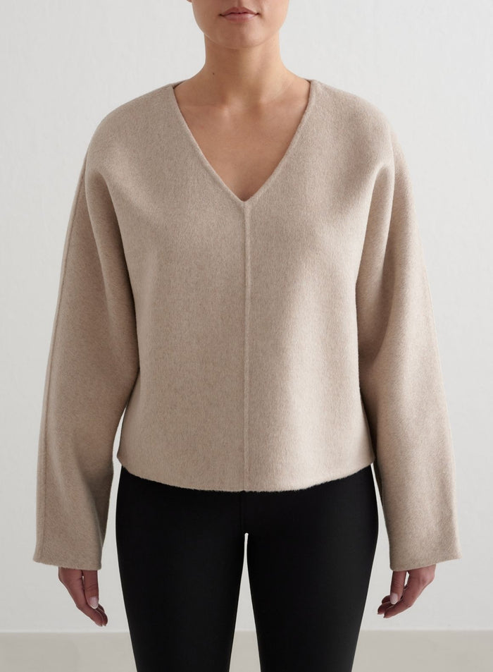 Beige aim'n Wool Sweatshirt V-aukolla ja pehmeällä villalla, yhdistettynä mustiin leggingseihin. [M - 175 cm]