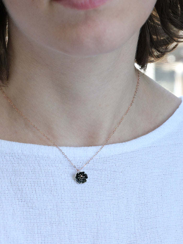 Close-up of a woman wearing a rose gold necklace with a small five-petal flower pendant – minimalist floral jewelry by Ardor Boutique