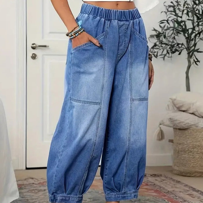 Front view of blue denim capri pants, with an elastic high waist, curved patch pockets, wide legs, and cropped gathered hems.