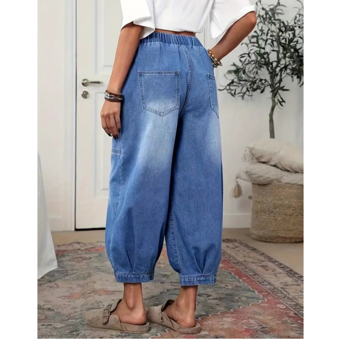 Back view of blue denim capri pants with elastic waistband, square rear pockets, wide barrel legs, and cropped gathered hems.