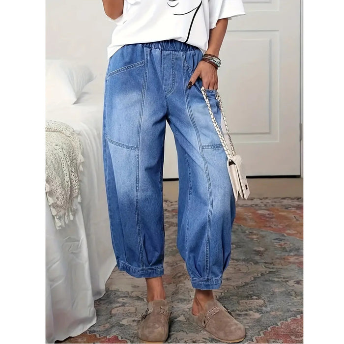Blue high rise capri jeans styled with a white graphic top, shoulder bag, tan slip-on shoes, and relaxed everyday accessories
