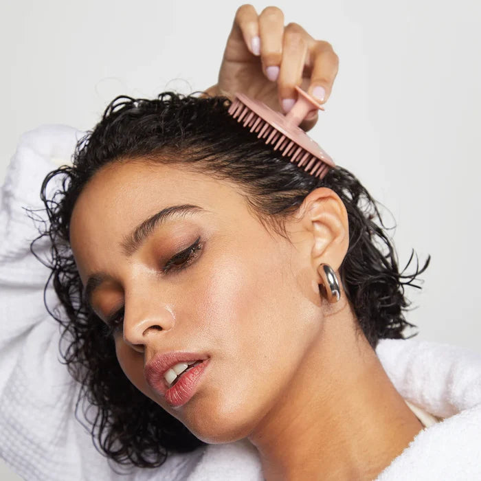 Woman combing her hair with scalp brush