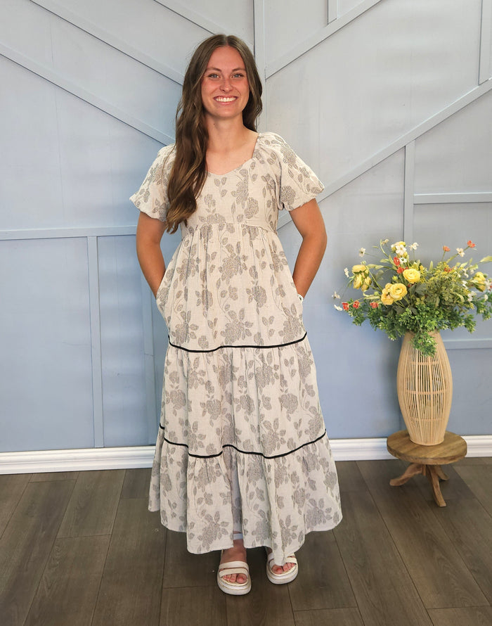 Girl wearing long gray tiered dress with floral print.