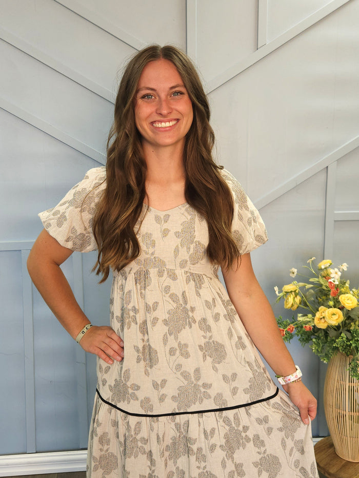Girl wearing long gray tiered dress with floral print.