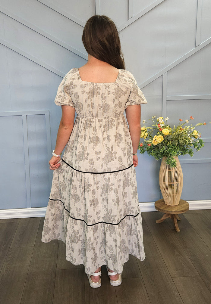 Girl wearing long gray tiered dress with floral print.