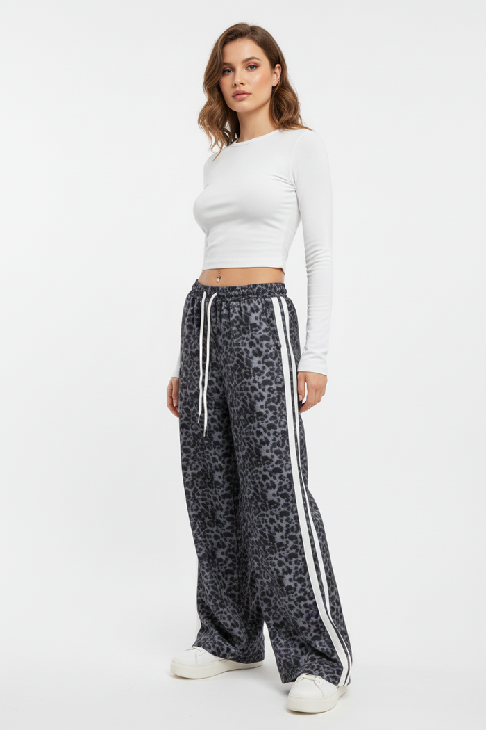 Woman wearing a white long-sleeve top and leopard print pants with white stripes on a white background
