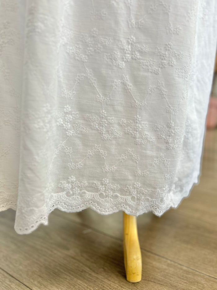White embroidered dress with scalloped hem.
