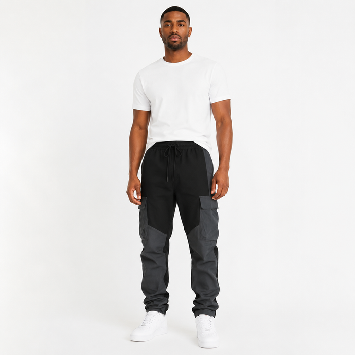 Men's black loose fit cargo trousers front view with large pockets and charcoal stitched panels