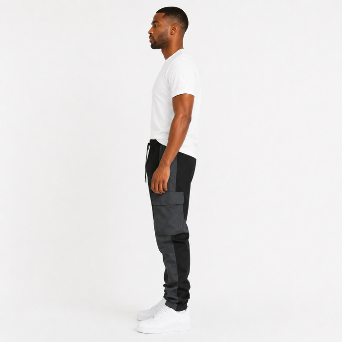 Men's black cargo trousers side view showing large flap pocket and two-tone panel design