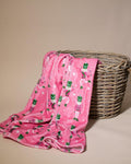 Pink and green nutcracker patterned throw draped over a wicker basket