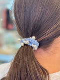 Blue hair tie with pearls in a ponytail.