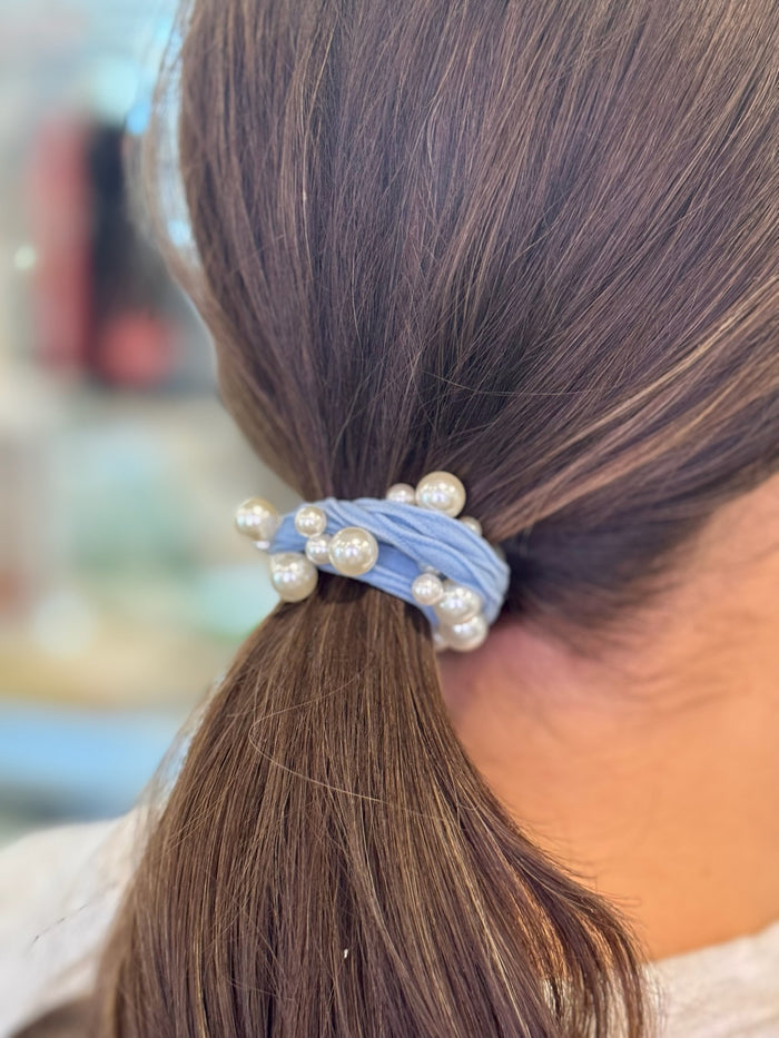 Blue hair tie with pearls in a ponytail.