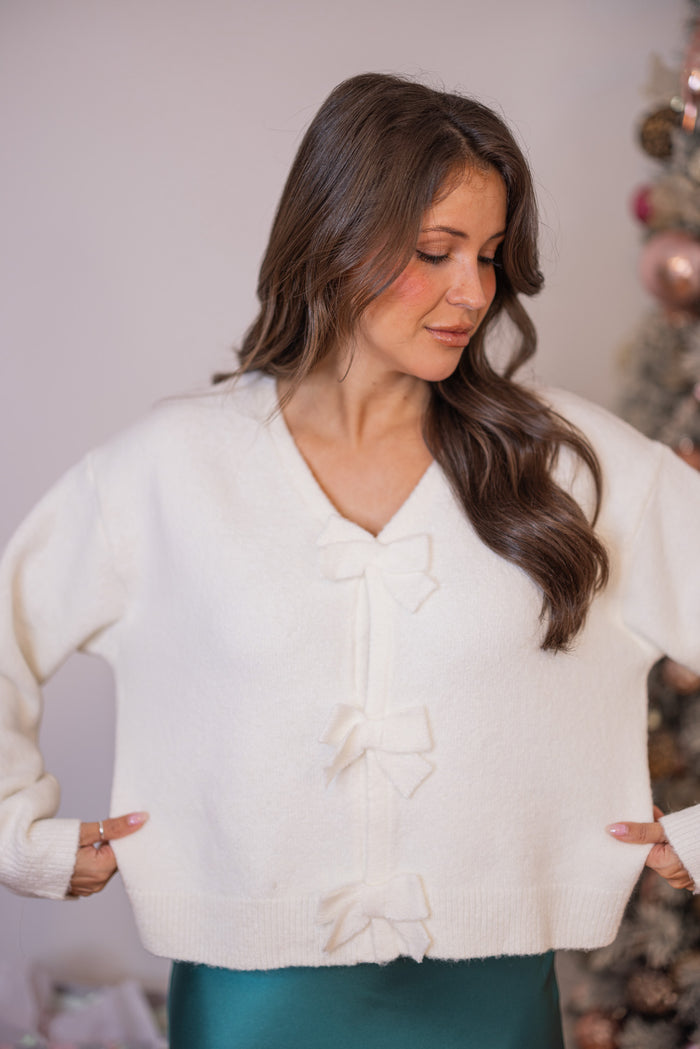 Women's cropped off white sweater with snap front bow tie closures by Wishlist showing semi-cropped length