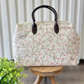 Beige zipper top bag with pink embroidered blossoms.