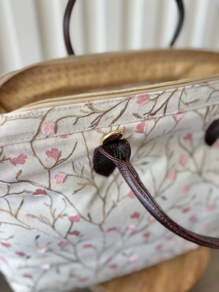Beige zipper top bag with pink embroidered blossoms.