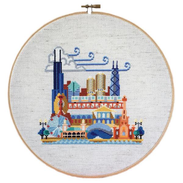Cross-stitch of Chicago landmarks including the Willis Tower and Ferris wheel, framed in a wooden hoop.