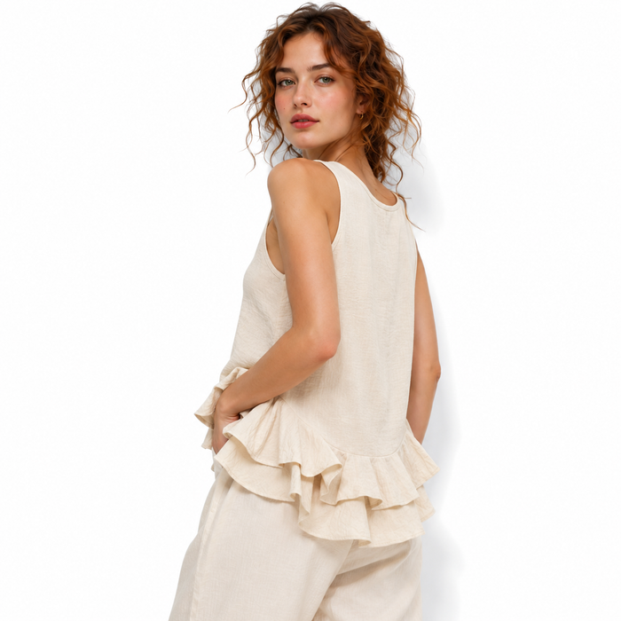 Woman wearing a cream-colored sleeveless top with ruffled layers on a white background