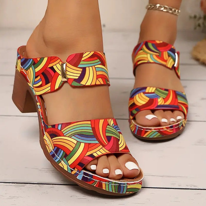 Women's printed slide sandals with a round open toe, buckle detail and graphic print, shown for casual summer outfit styling.