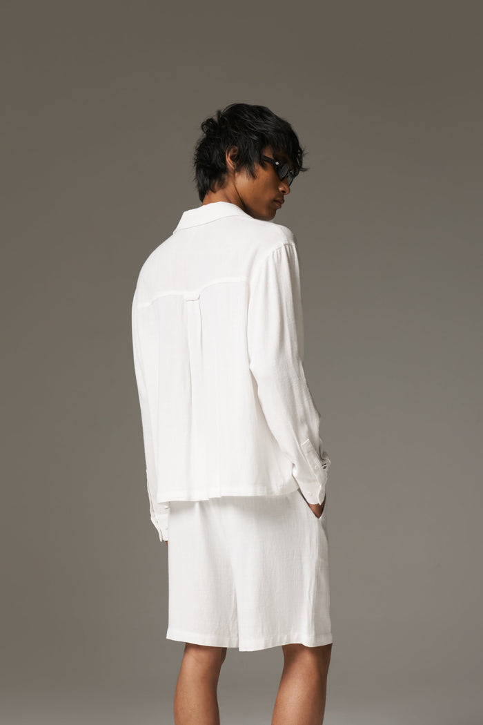 Person wearing a white outfit against a grey background