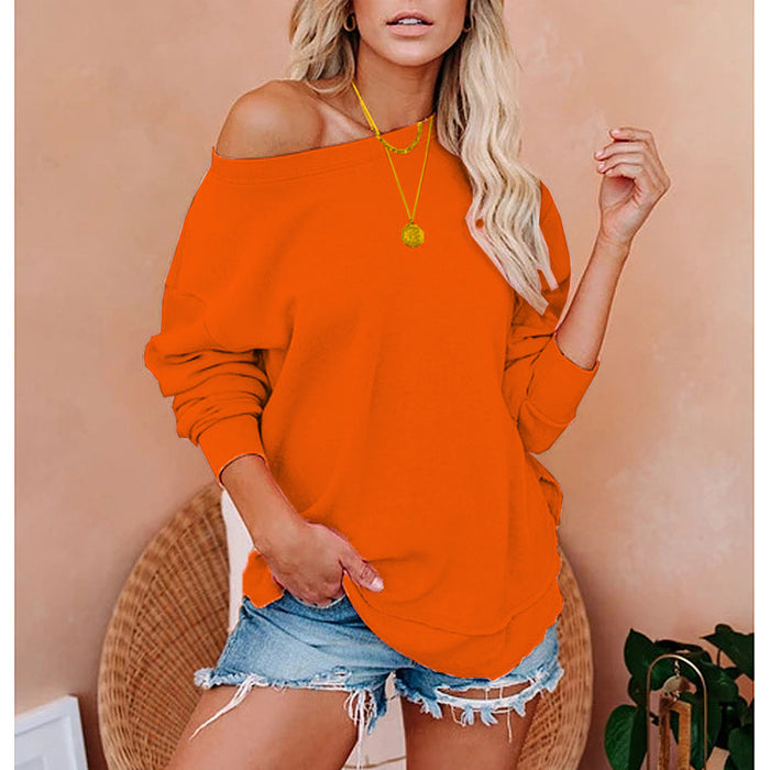 Woman wearing an orange off-shoulder top and denim shorts against a beige wall.