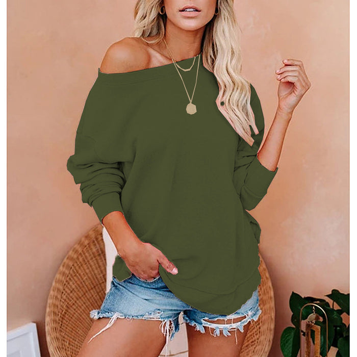 Woman wearing an olive green off-shoulder top with denim shorts against a beige wall.