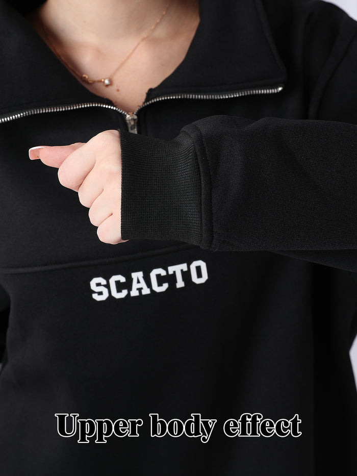 Person wearing a black jacket with 'SCACOTO' branding, pointing to the chest area.