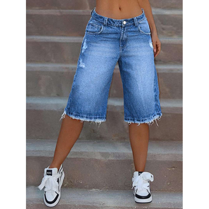 Person wearing blue denim shorts and white sneakers on a staircase.