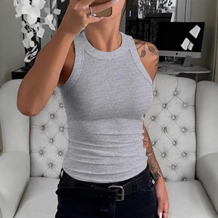 Person wearing a gray tank top sitting on a tufted chair in a room.
