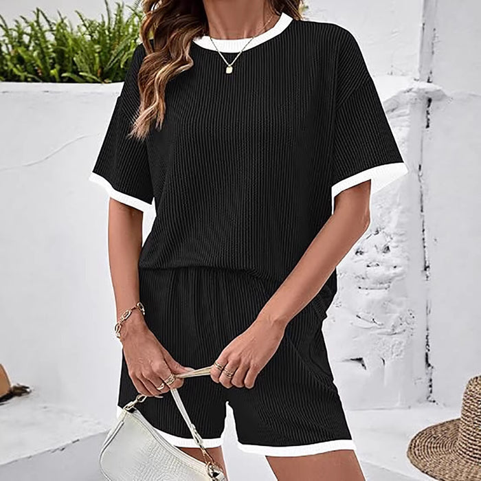 Woman wearing a black outfit with white trim against a white wall.